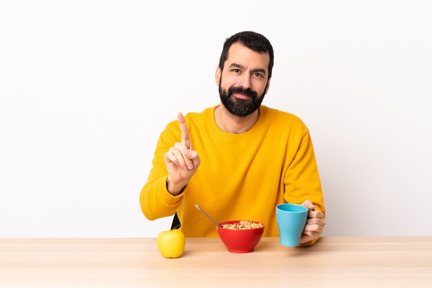 Kaukasischer Mann, der Frühstück in einer Tabelle zeigt und einen Finger hebt.