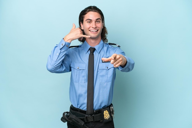 Kaukasischer Mann der jungen Polizei lokalisiert auf blauem Hintergrund, der Telefongeste macht und nach vorne zeigt