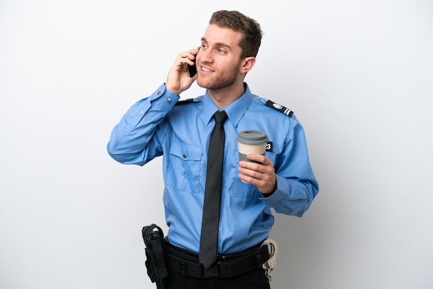 Kaukasischer Mann der jungen Polizei lokalisiert auf weißem Hintergrund, der Kaffee zum Mitnehmen und ein Handy hält