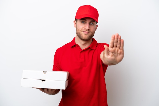 Foto kaukasischer mann der pizzalieferung mit arbeitsuniform, der pizzaschachteln lokalisiert auf weißem hintergrund aufhebt und stoppgeste macht