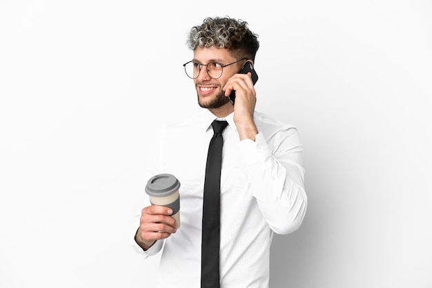 Kaukasischer Mann des Geschäfts lokalisiert auf weißem Hintergrund, der Kaffee zum Mitnehmen und ein Handy hält