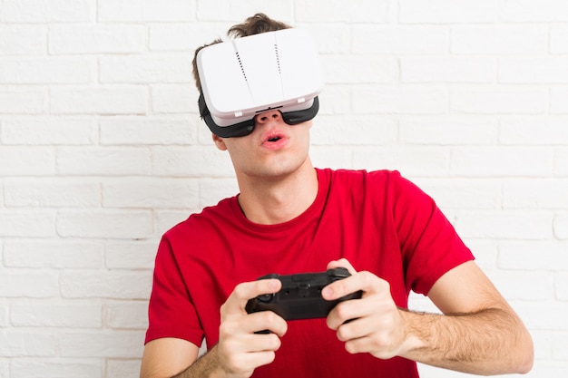 Kaukasischer mann des jugendlichen, der gläser der virtuellen realität und gamecontroller verwendet