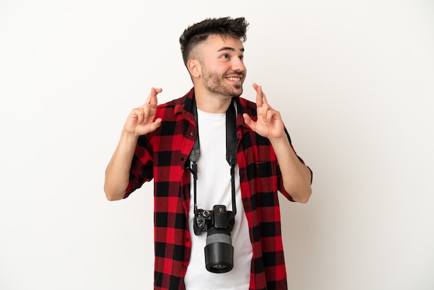 Kaukasischer Mann des jungen Fotografen lokalisiert auf weißem Hintergrund mit kreuzenden Fingern