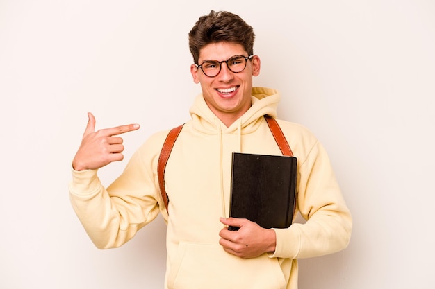 Kaukasischer Mann des jungen Studenten lokalisiert auf weißer Hintergrundperson, die eigenhändig auf einen Hemdkopienraum stolz und selbstbewusst zeigt