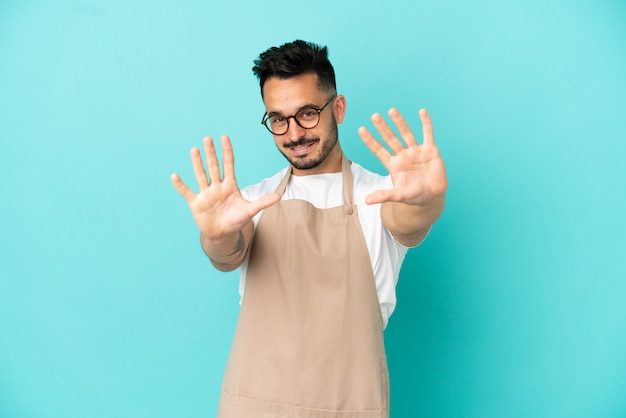 Kaukasischer Mann des Restaurantkellners lokalisiert auf blauem Hintergrund, der mit den Fingern zehn zählt