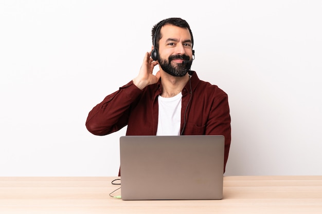 Kaukasischer Mann des Telemarketers, der mit einem Headset und mit lachendem Laptop arbeitet.