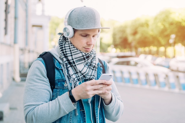 Kaukasischer Mann in einer grauen Kappe kommuniziert in sozialen Netzwerken über Smartphone