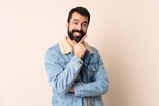 Kaukasischer Mann mit Bart über Wand glücklich und lächelnd