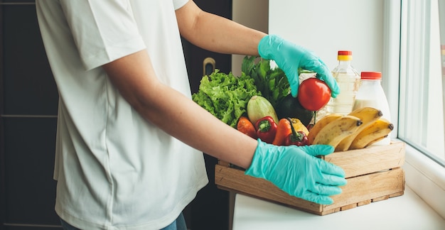 Kaukasischer Mann mit grünen medizinischen Handschuhen nach dem Kauf von Produkten für zu Hause während der Quarantäne