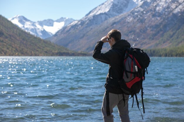 Kaukasischer Mann mit Rucksack schöne Berg- und Flusslandschaft Reisewanderer, der wegschaut