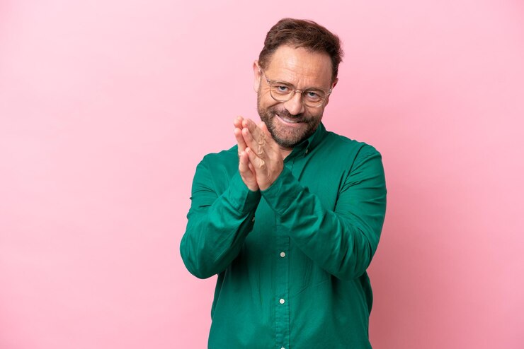 Foto kaukasischer mann mittleren alters isoliert auf rosafarbenem hintergrund, der nach einer präsentation auf einer konferenz applaudiert