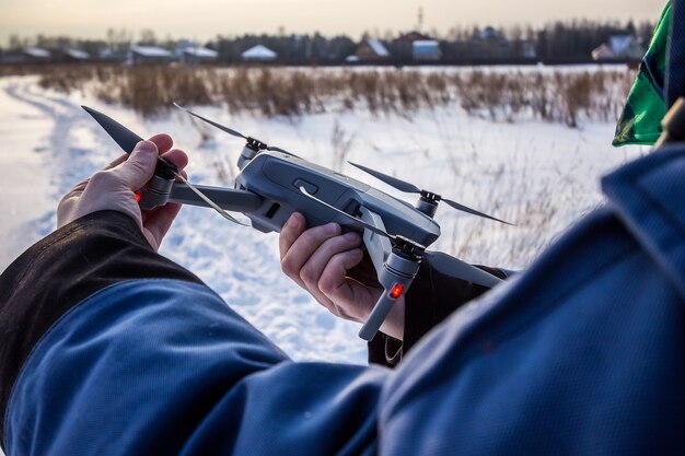 Kaukasischer Mann von 30 Jahren, der Drone im verschneiten Feld im Winter fliegt.