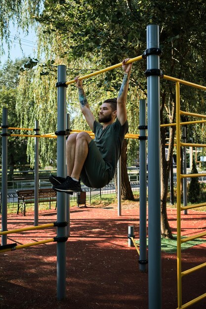 Kaukasischer Mann zieht sich an warmen Sommermorgen auf dem Straßensportplatz hoch