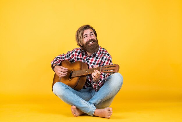 Kaukasischer reifer Hipster-Gitarrenpalyer mit trendiger Frisur im karierten Hemd liebt Musiksänger