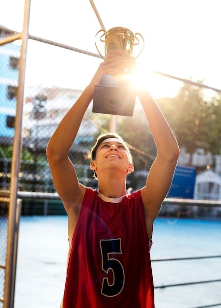 Kaukasischer Teenager in der sportlichen Kleidung, die draußen eine Trophäe hält