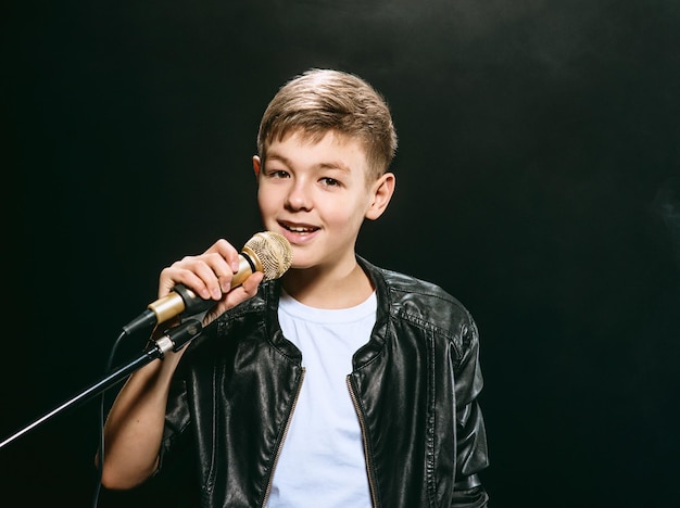 Kaukasischer Teenager in weißem T-Shirt, Blue Jeans und Lederjacke mit Mikrofongesang