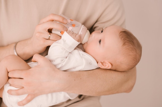 Kaukasischer Vater füttert neugeborenes Mädchen aus einer Flasche Elternteil, das einen schaukelnden Kind-Tochter-Sohn in den Händen hält Authentischer Lebensstil Elternschaft Vaterschaftsmoment