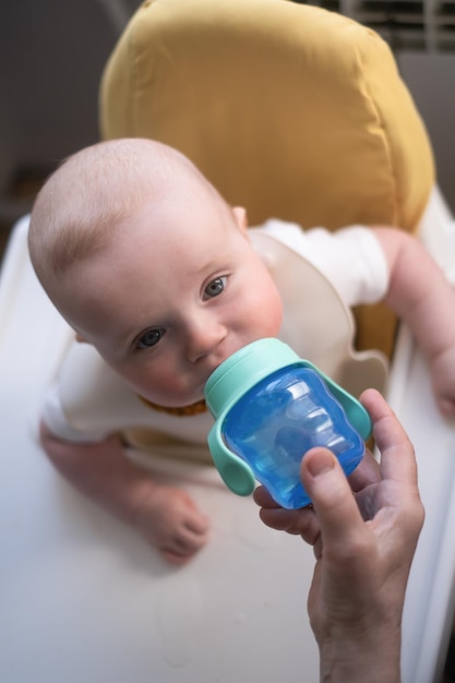 Kaukasisches Baby, das Flasche und Trinkwasser hält