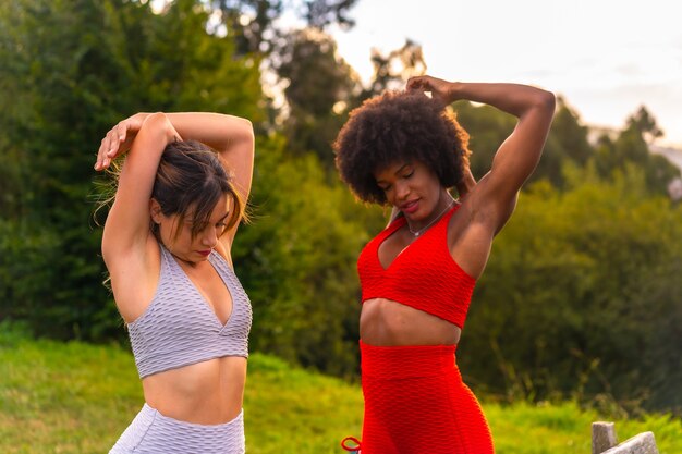 Kaukasisches blondes Mädchen und dunkelhäutiges Mädchen mit Afro-Haaren beim Dehnen