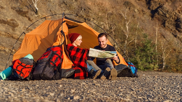 Kaukasisches Hipsterpaar, das Karte im Berg erforscht