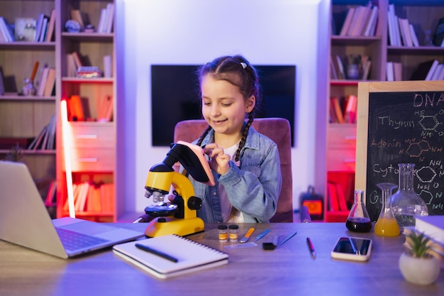 Kaukasisches Kind in Freizeitkleidung studiert, indem es abends zu Hause Wissenschaft macht