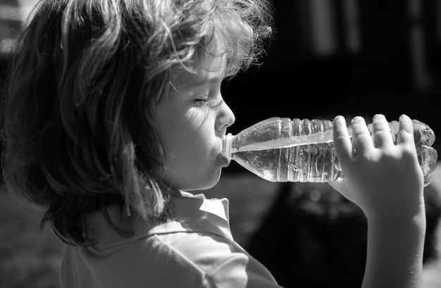 Foto kaukasisches kind trinkt wasser im freien im park porträt nahbild kinder gesicht