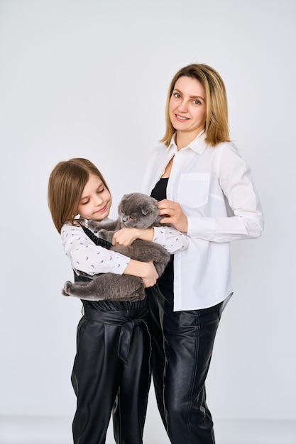 Kaukasisches kleines Mädchen mit ihrer Mutter hält Katze in den Armen isoliert auf weiß