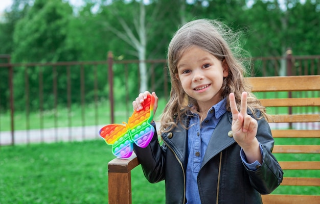 Kaukasisches kleines Mädchen spielt mit Pop-It-Silikon trendiges Regenbogen-Colow-Spielzeug