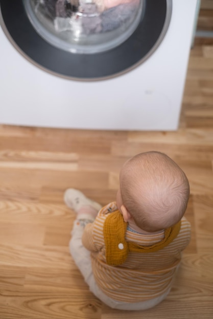 Kaukasisches Mädchen, das mit Waschmaschine spielt und einen Prozess beobachtet