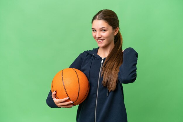 Kaukasisches Mädchen des Teenagers, das Basketball über lokalisiertem Hintergrund spielt, lacht