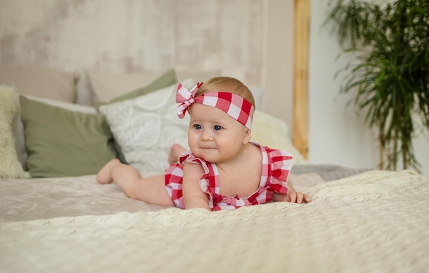 Foto kaukasisches mädchen in einem karierten bodysuit kriecht auf dem bett im zimmer