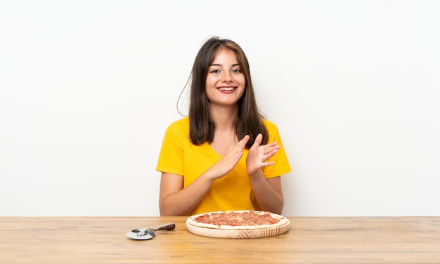 Kaukasisches Mädchen mit einer Pizza applaudierend