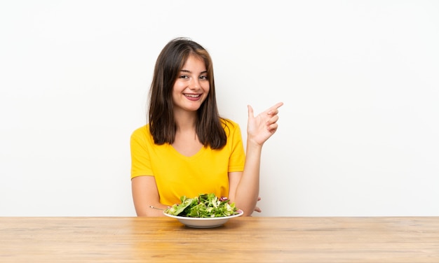 Kaukasisches Mädchen mit Salat Finger auf die Seite zeigend