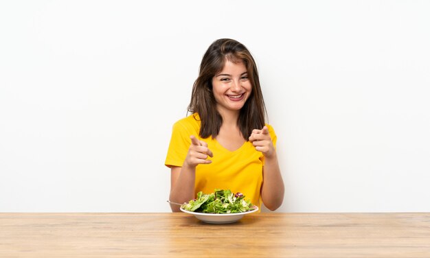 Kaukasisches Mädchen mit Salat zeigt Finger auf Sie