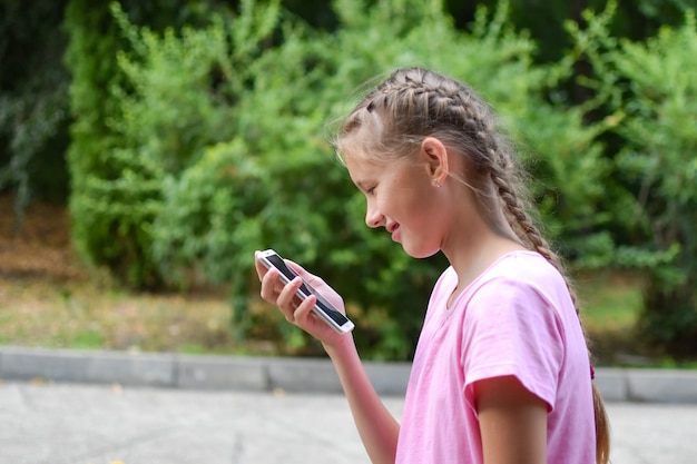 Kaukasisches Mädchen mit Telefon im Freien. Internetkommunikation per SMS. Online-Chat Teenager.