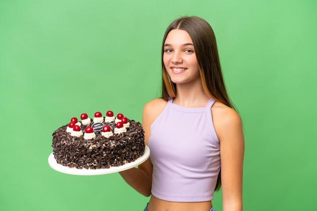 Kaukasisches Teenagermädchen, das Geburtstagstorte über isoliertem Hintergrund hält und viel lächelt