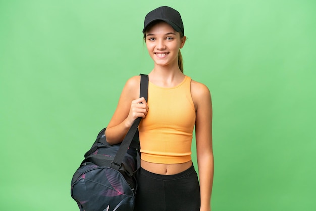 Kaukasisches Teenagermädchen mit Sporttasche über isoliertem Hintergrund, das viel lächelt