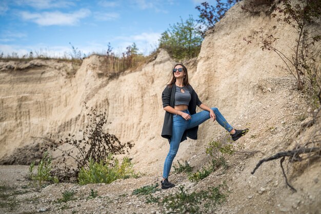 Kaukasisches weibliches Model posiert im Sandsteinbruch mit blauem Himmel, im Sommer sonniger Tag, Lifestyle