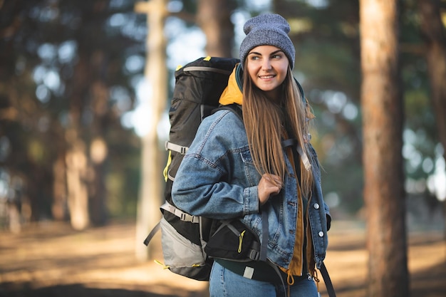 Kaukasisches weißes Mädchen mit einem großen Wanderrucksack im Wald Herbstfarben