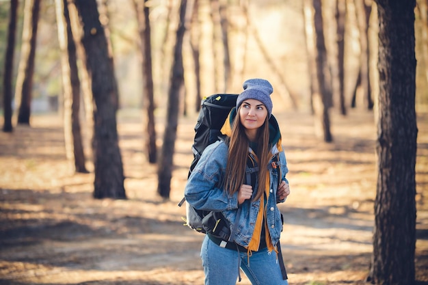 Kaukasisches weißes Mädchen mit einem großen Wanderrucksack im Wald