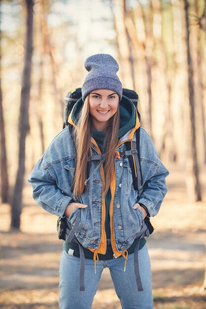 Kaukasisches weißes Mädchen mit einem großen Wanderrucksack im Wald