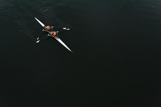 Kayak en canoa con remadores en un fondo de vista superior de agua oscura