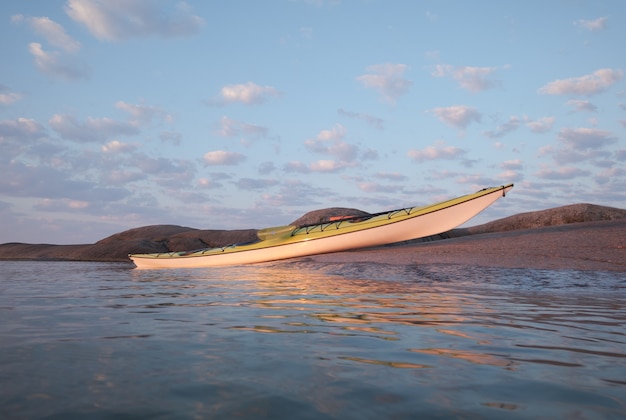 Kayak de mar amarrado a la orilla de granito. Temas de turismo activo