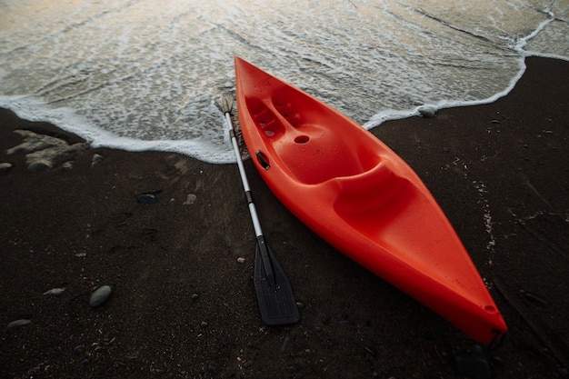 Kayak naranja con remo junto al mar