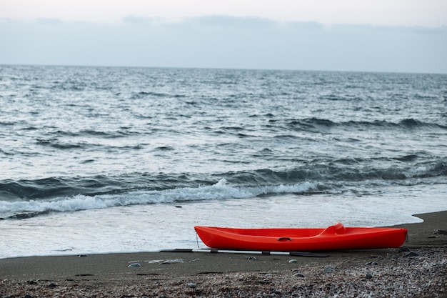 Kayak naranja con remo junto al mar