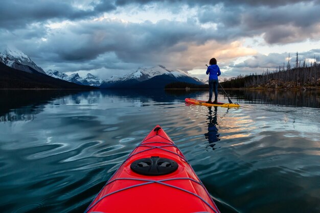 Kayak y Paddle Board en un apacible lago glaciar con las Montañas Rocosas Canadienses