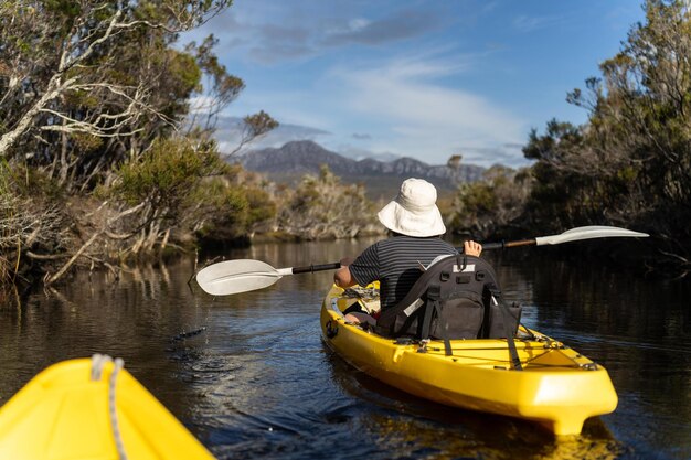 Kayaking um rio em uma canoa com montanhas em um deserto em um parque nacional com plantas nativas e árvores em uma floresta tropical na austrália com rios e explorar na austrália