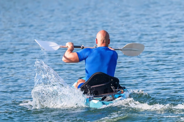 Kayakista joven remando en kayak. Deportista en kayak Blue Water.