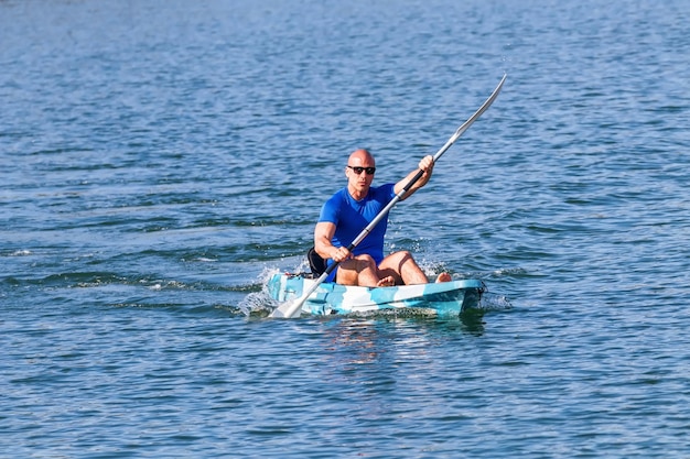 Kayakista joven remando en kayak. Deportista en kayak Blue Water.