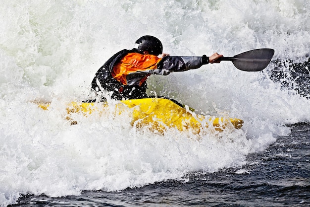 Foto un kayakista masculino activo rodando y surfeando en aguas turbulentas